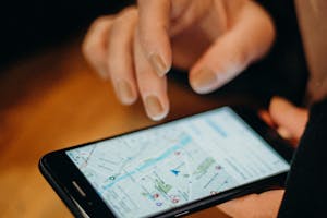 Close-up of a hand using a smartphone displaying a map for navigation.